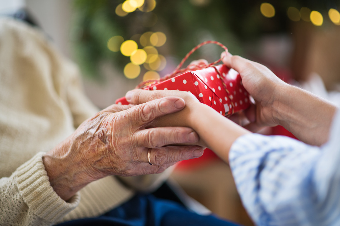 Close-up of hands of senior and young woman holding a present at Christmas time.